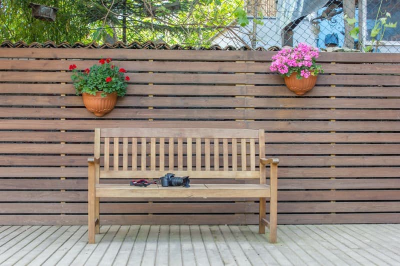 wood privacy fence beside decorative white picket fence comparison