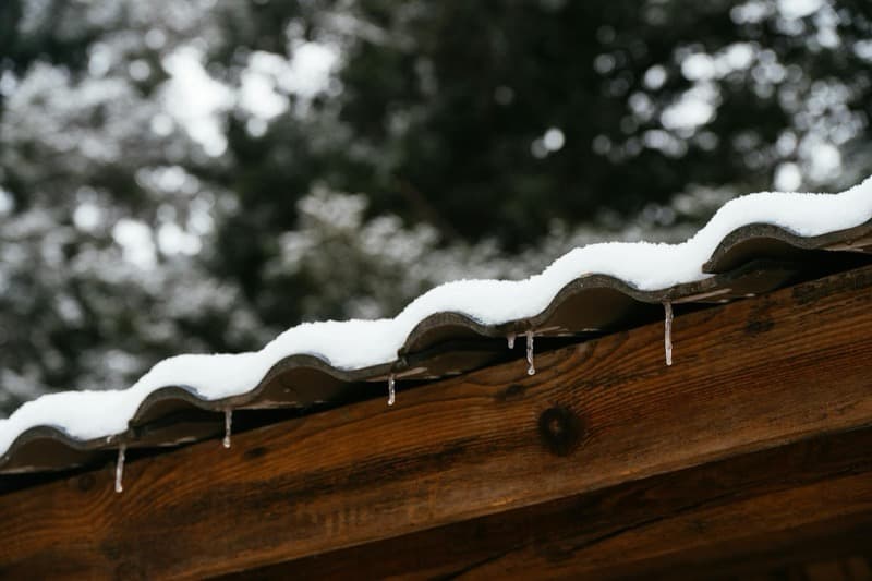 ice dam forming at roof eave with icicles blocking gutter flow